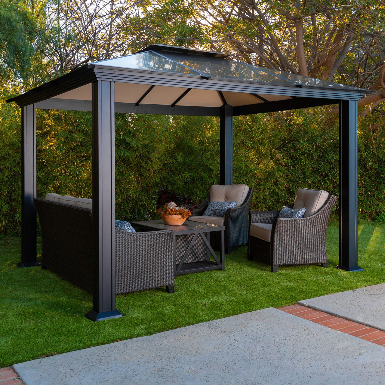 Outdoor gazebo with seating and a table on green grass.