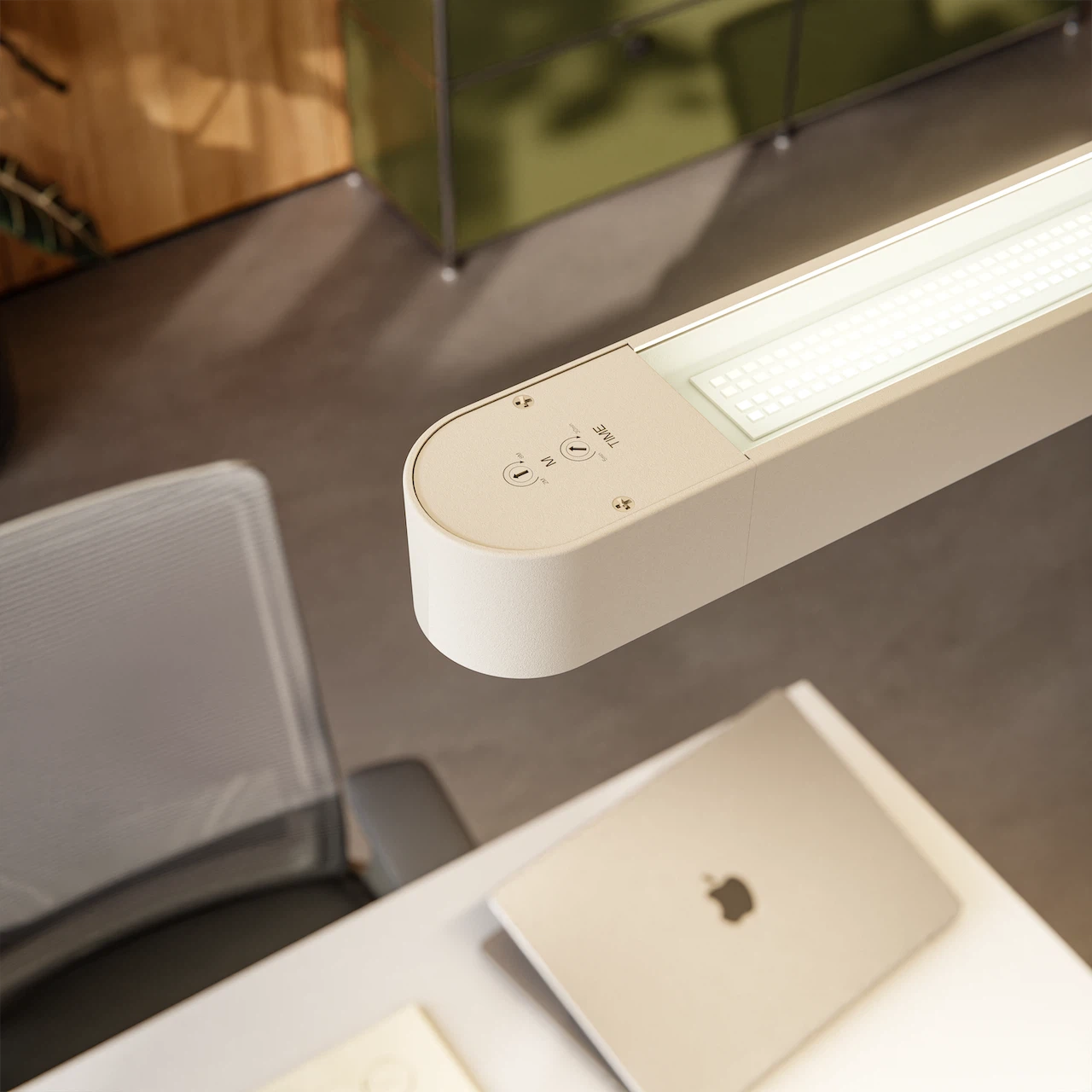 Close-up of the white lamp head of the " Lumino Pro" floor lamp, featuring control buttons for the timer and motion sensor, above an office desk.