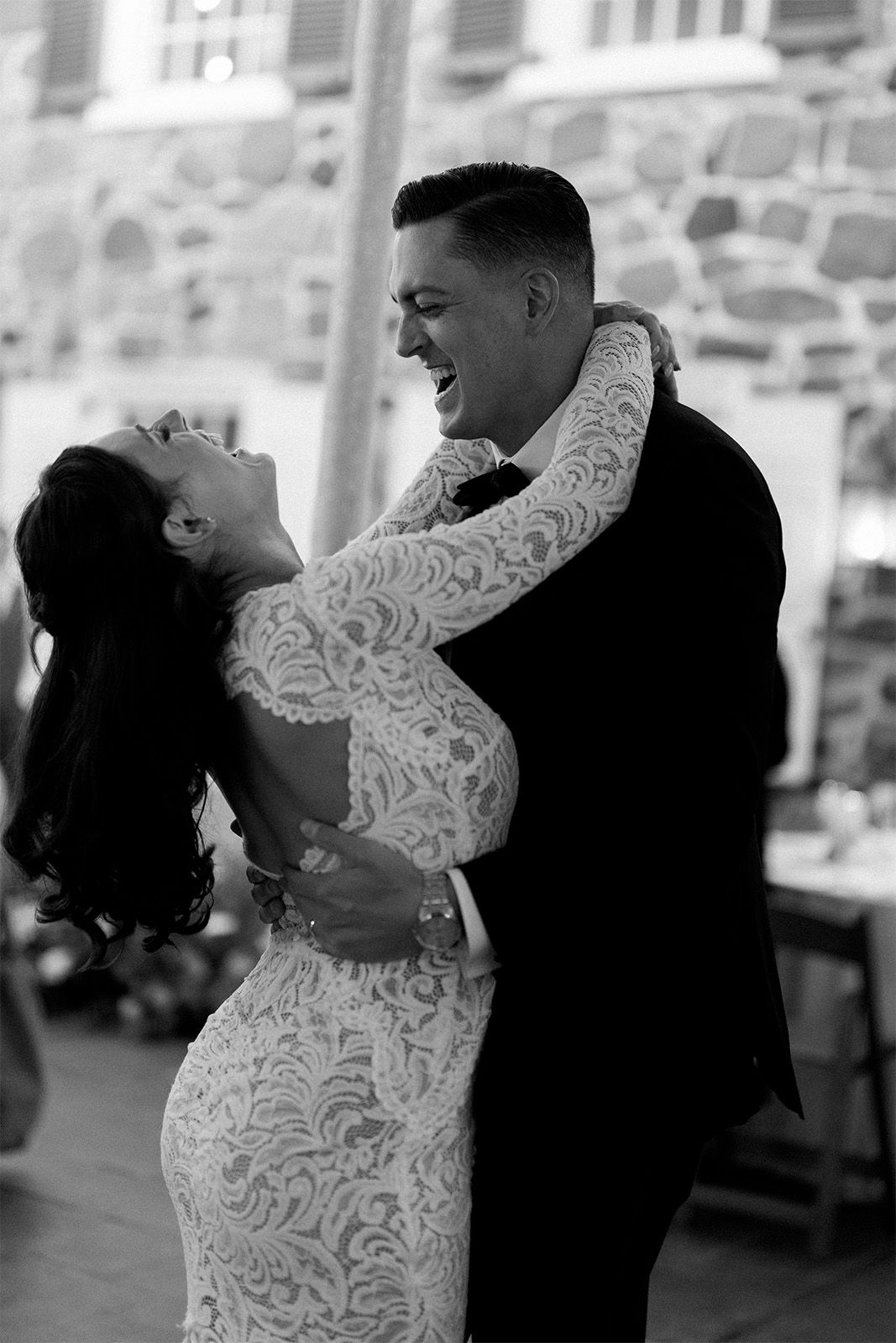 Couple dancing joyfully at a celebration, wearing elegant outfits.