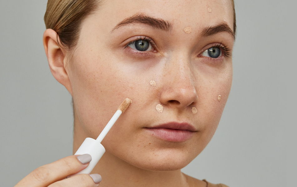 A woman applying serum to her face with a dropper.