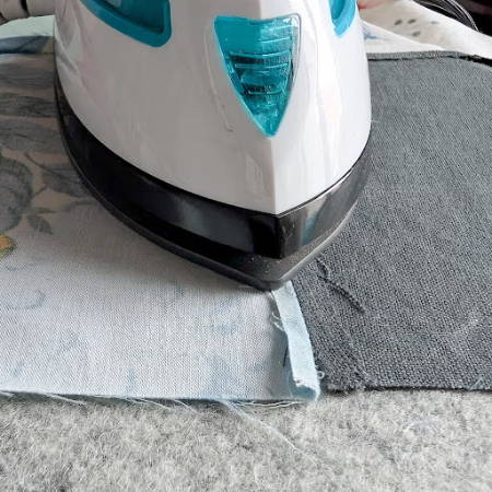 mini iron on a wool pressing mat pressing a seam of a quilt block