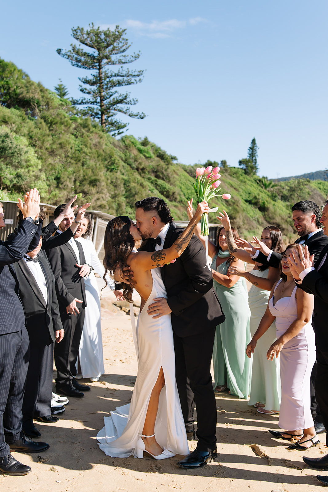 Couple kissing at a wedding celebration surrounded by friends and family.