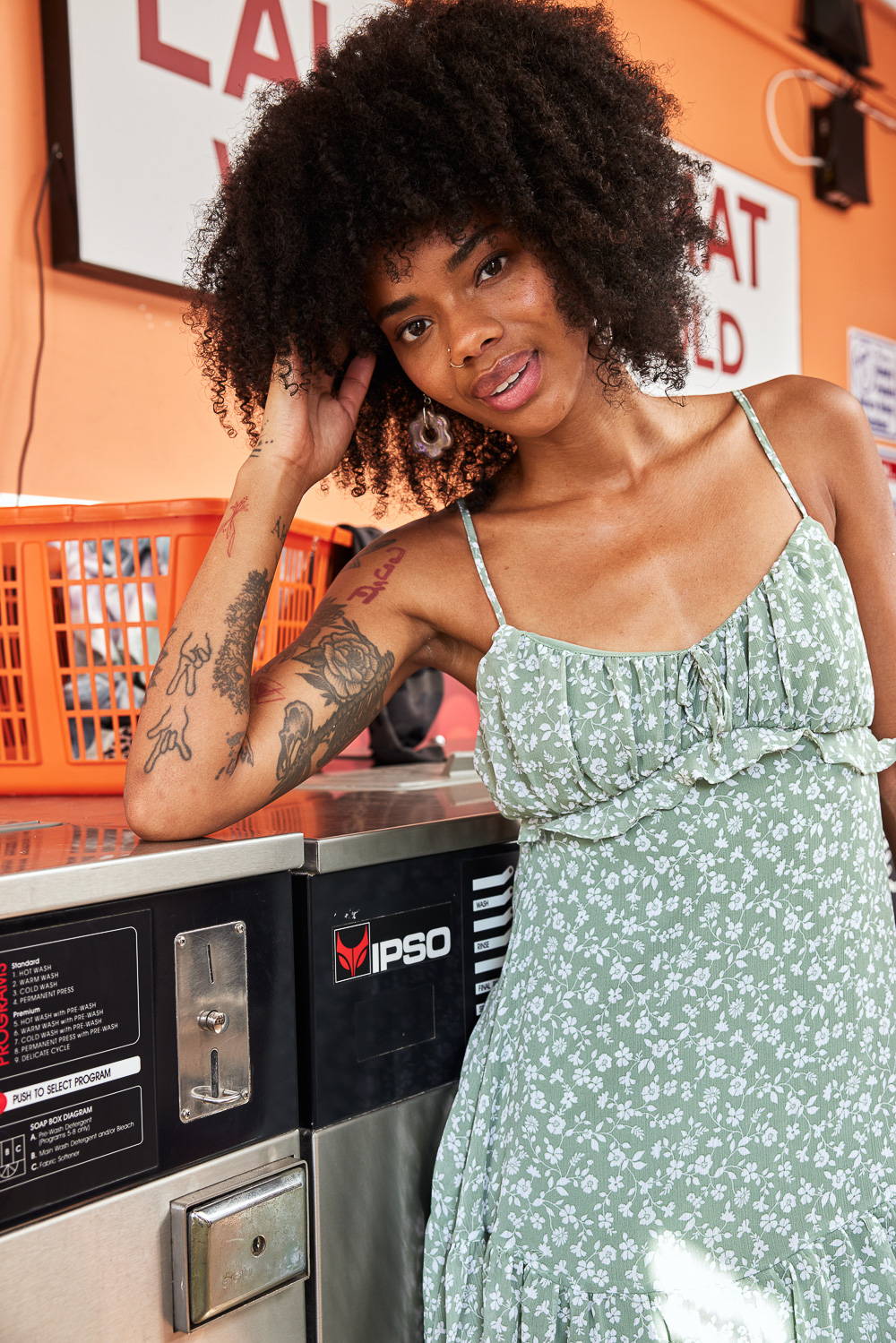 Trixxi Back to school embracing dorm life doing laundry in a laundromat in a sage green floral ruffle dress.