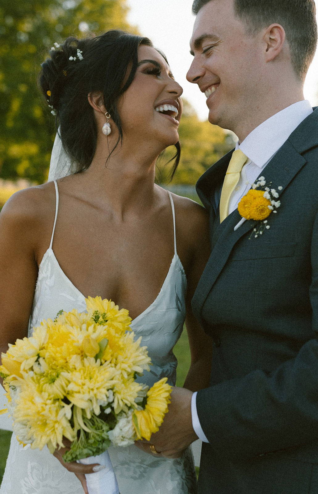 Braut und Bräutigam lachend mit gelbem Blumenstrauß
