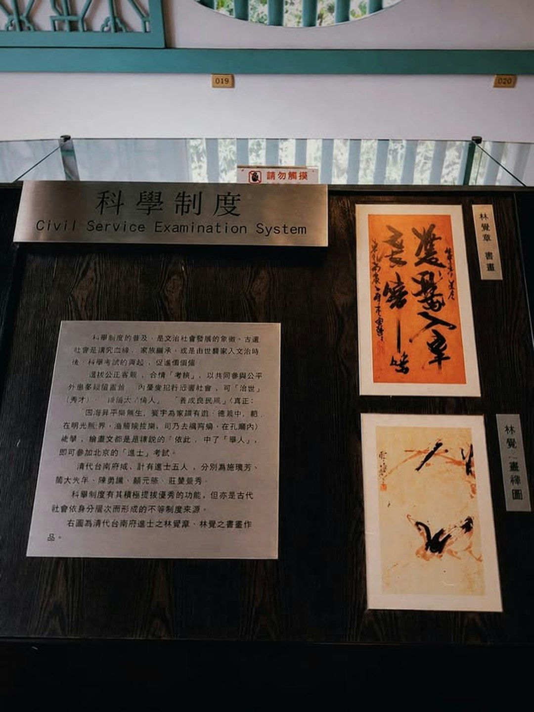 A museum display featuring a plaque about the Civil Service Examination System and calligraphy