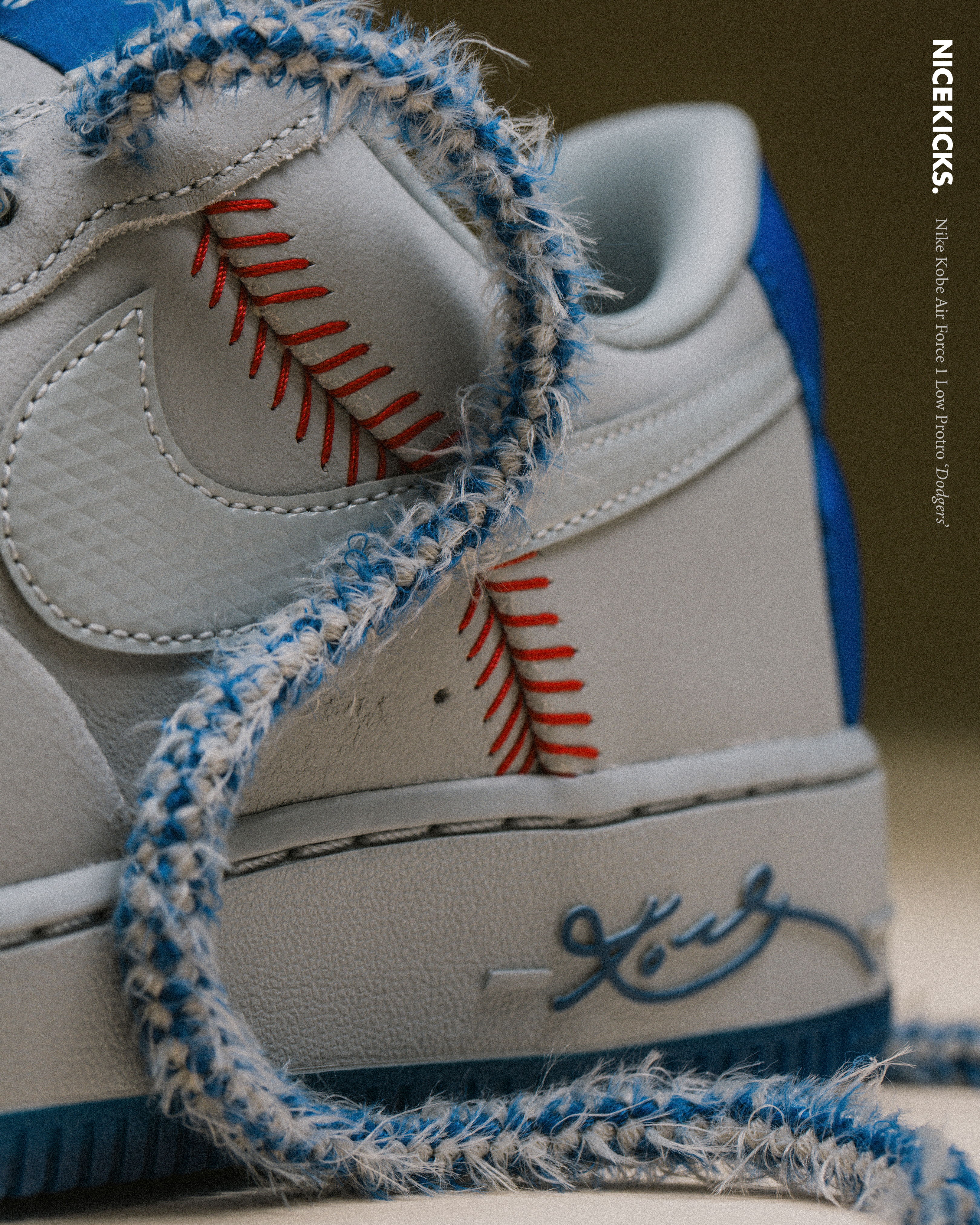 White sneaker with baseball-themed details and a blue lace.
