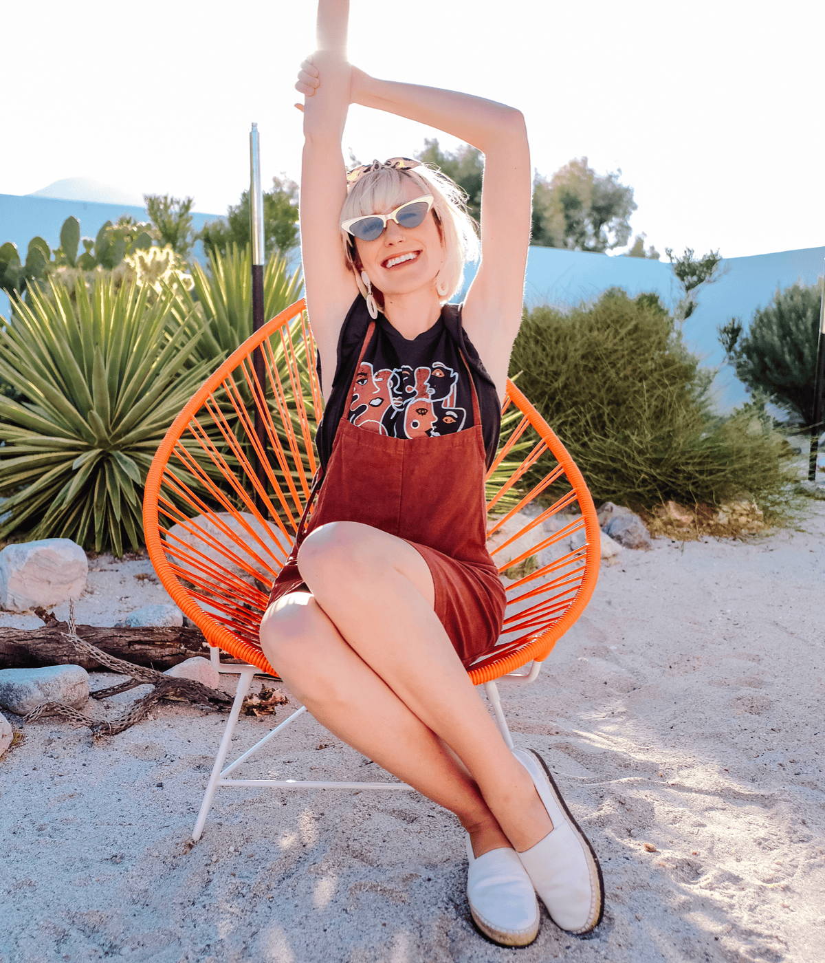 Dani Dazey on smiles with hands raised while sitting onboxhill's Acapulco lounge chair.
