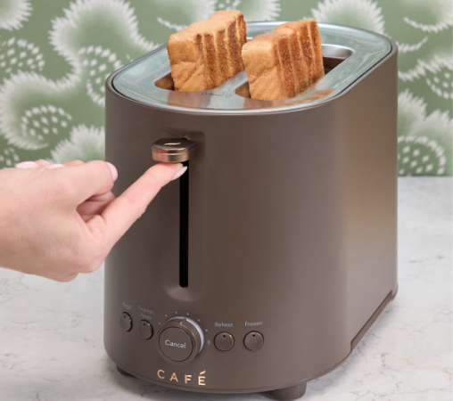 A hand pressing a button on a toaster with two slices of bread.