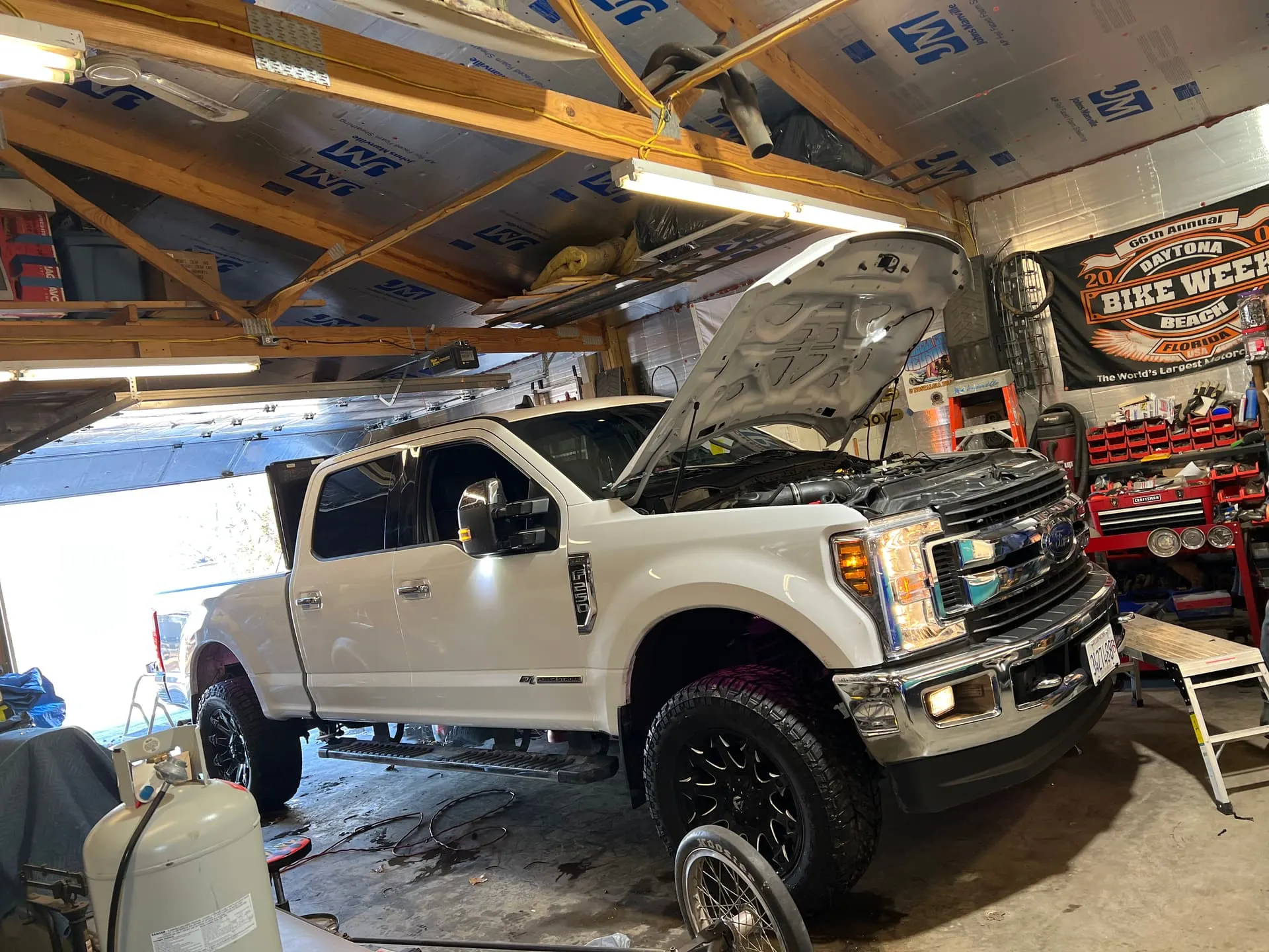 Jimmy's white 2019 Ford F250 Super Duty with hood open parked inside a garage