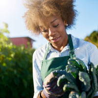 A close up of a woman holding some vegetables from the garden