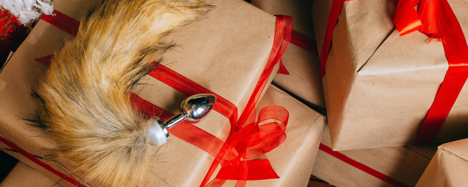 Metal anal plug with fur tail on top of gift boxes
