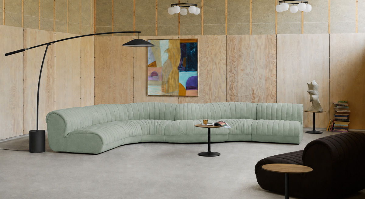 Modern living room with curved Coltre sofa, coffee table, and artistic decor.