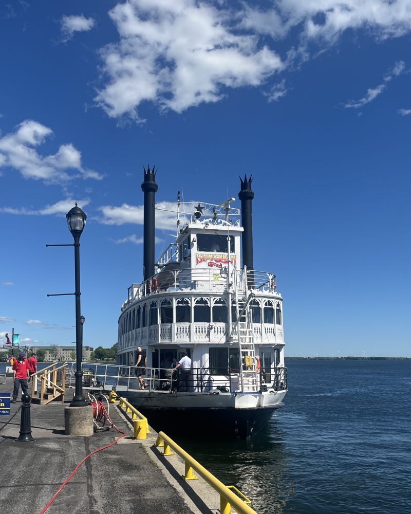 A steamboat docked at a pier under a blue sky.