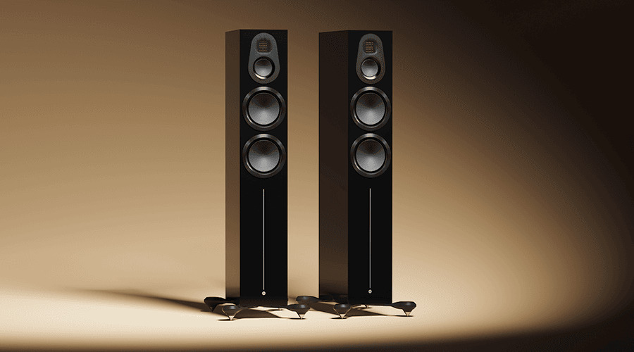 Two tall black speakers on a gradient background.