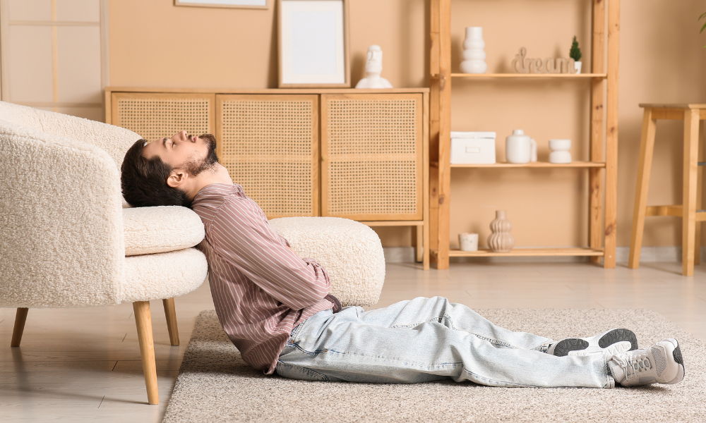 Person lying on the floor beside a sofa in a cozy room.