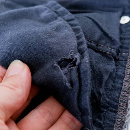 a hole in a pocket of jean trousers