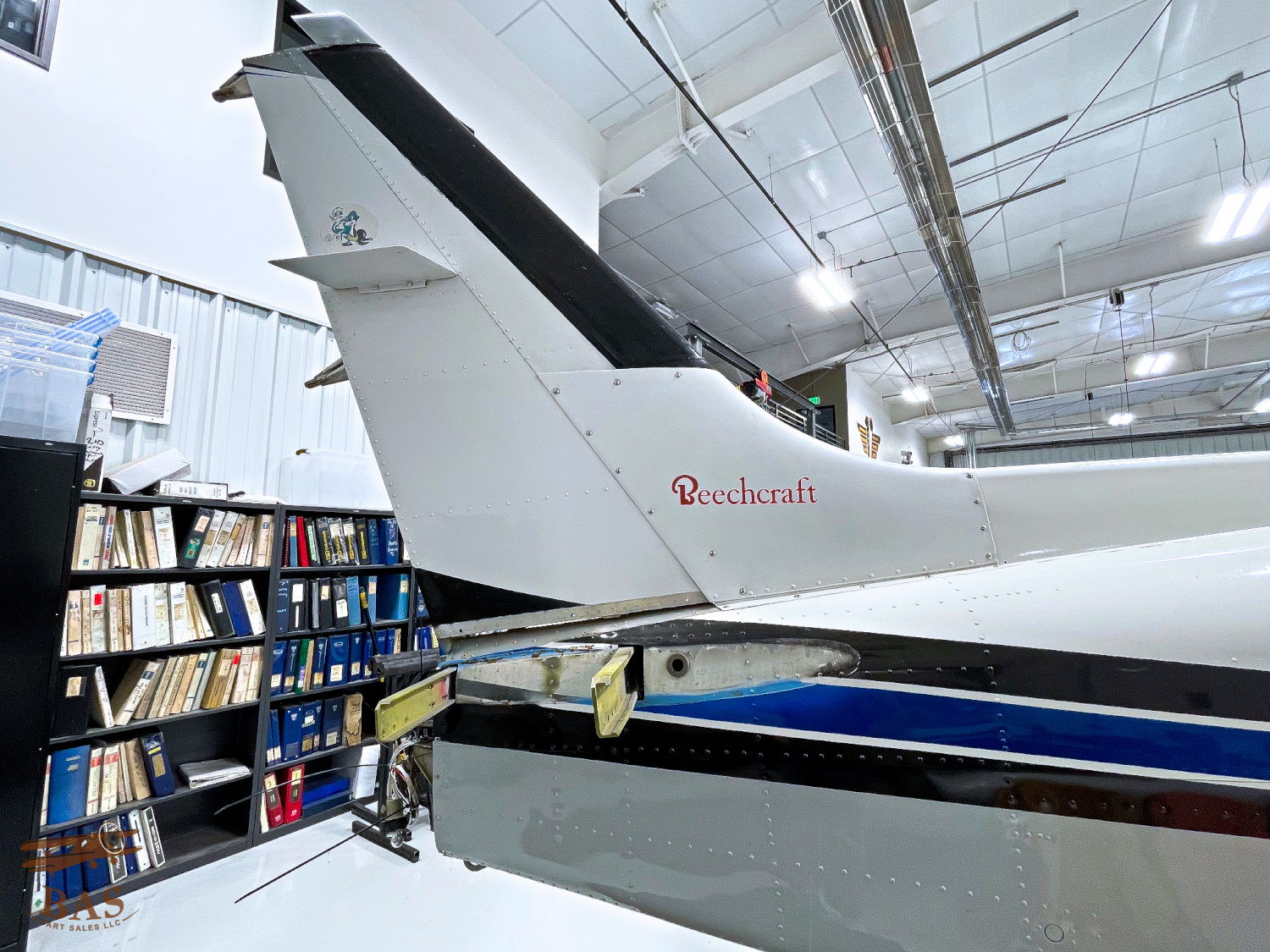 Tail of an aircraft with bookshelves in the background.