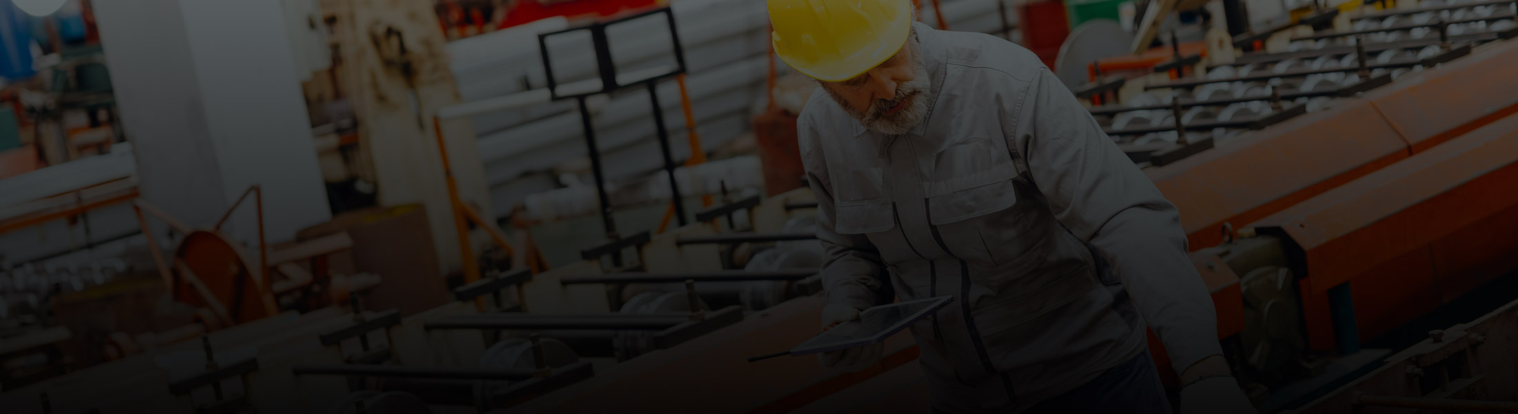 Worker in a manufacturing facility inspecting equipment, representing security and monitoring solutions for industrial and warehouse operations