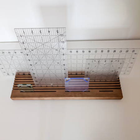a wooden quilt ruler holder holding various quilt rulers