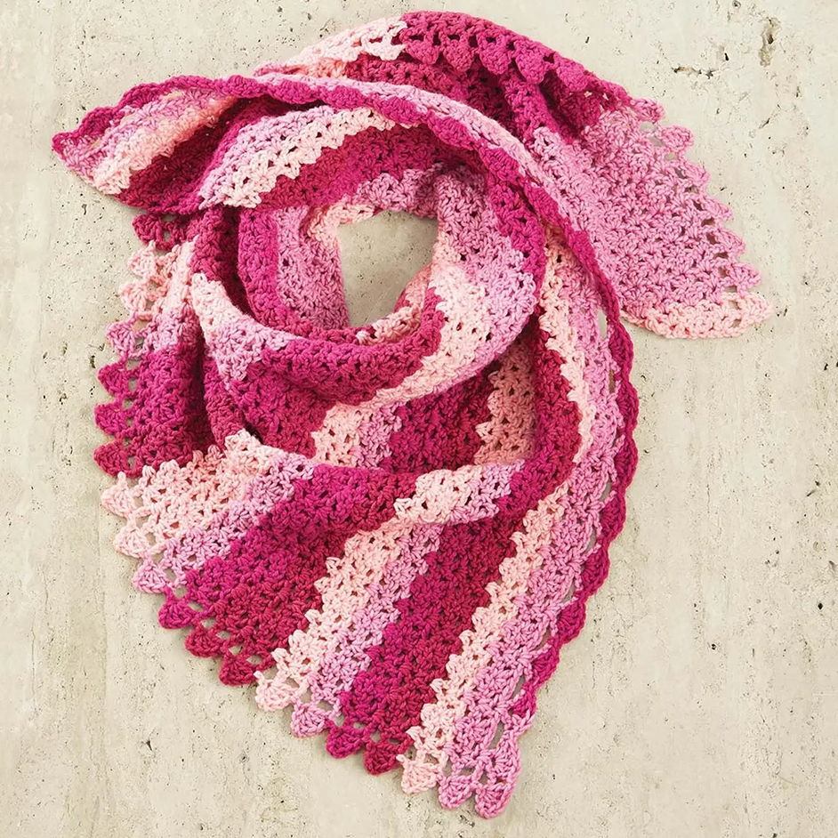 Crocheted scarf in shades of pink and white, arranged in a loop.