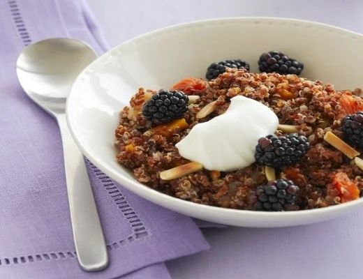 Bowl of quinoa topped with blackberries and yogurt.