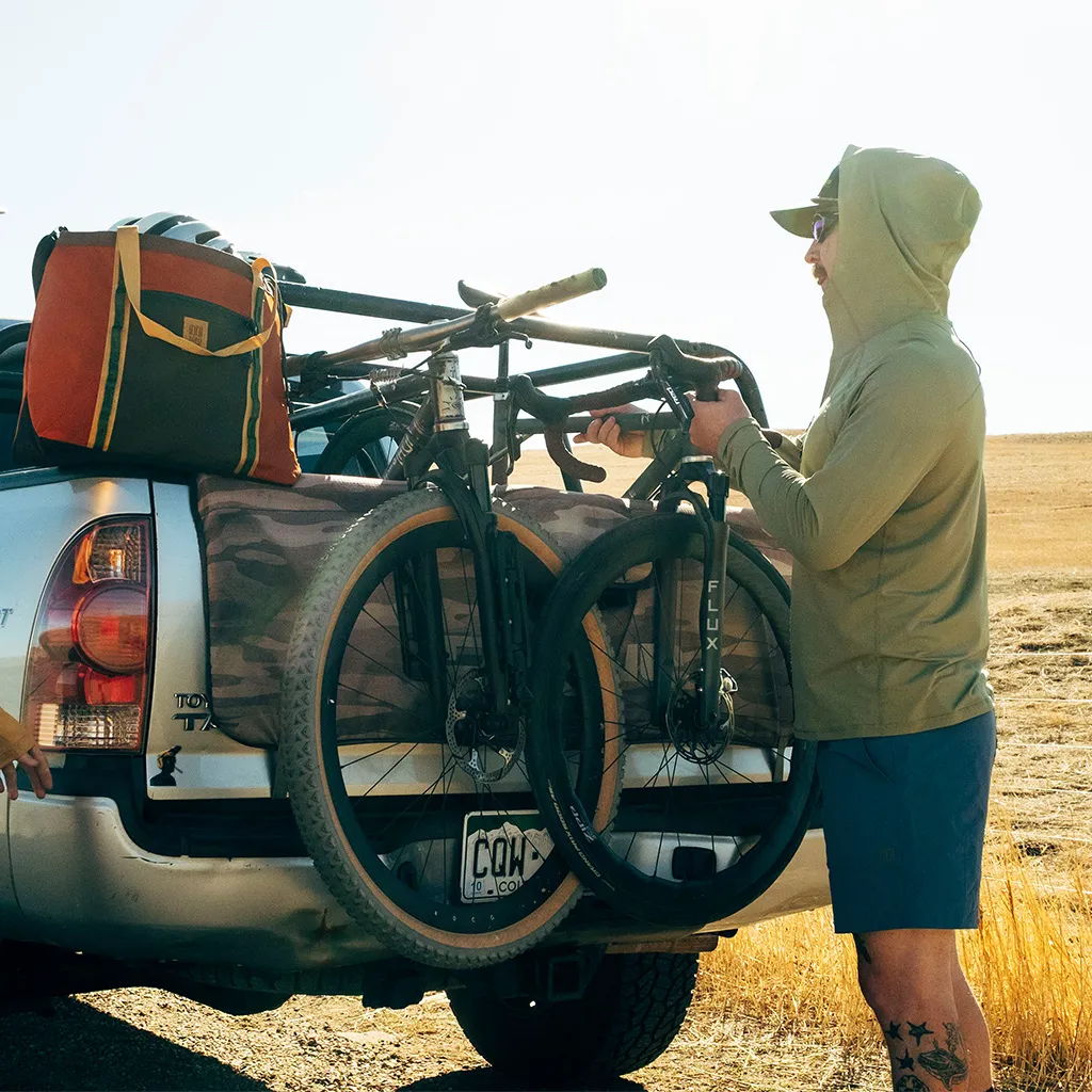 Person loading bicycles onto a truck in an outdoor setting.