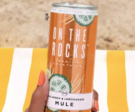 A hand holding a can of cocktail on a beach towel.