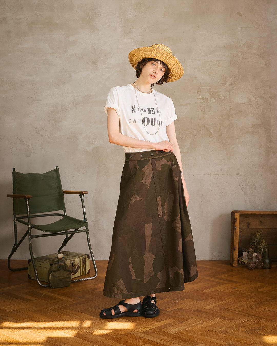 Woman in a stylish outfit with a hat, standing in a room.
