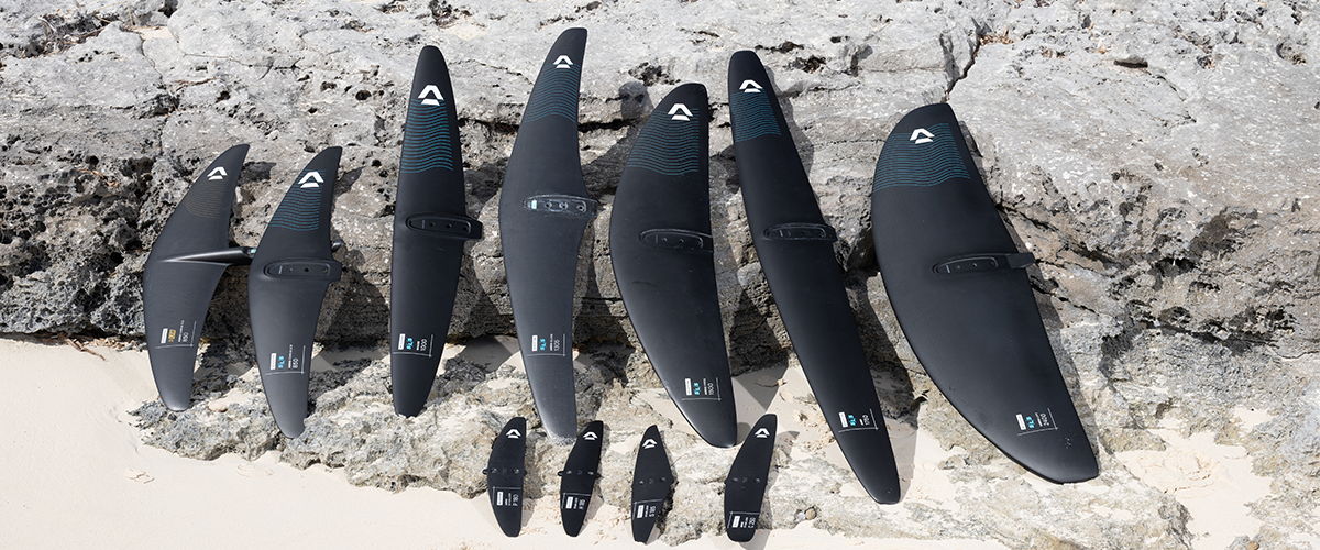 Various black surfboards lined up on a sandy beach.