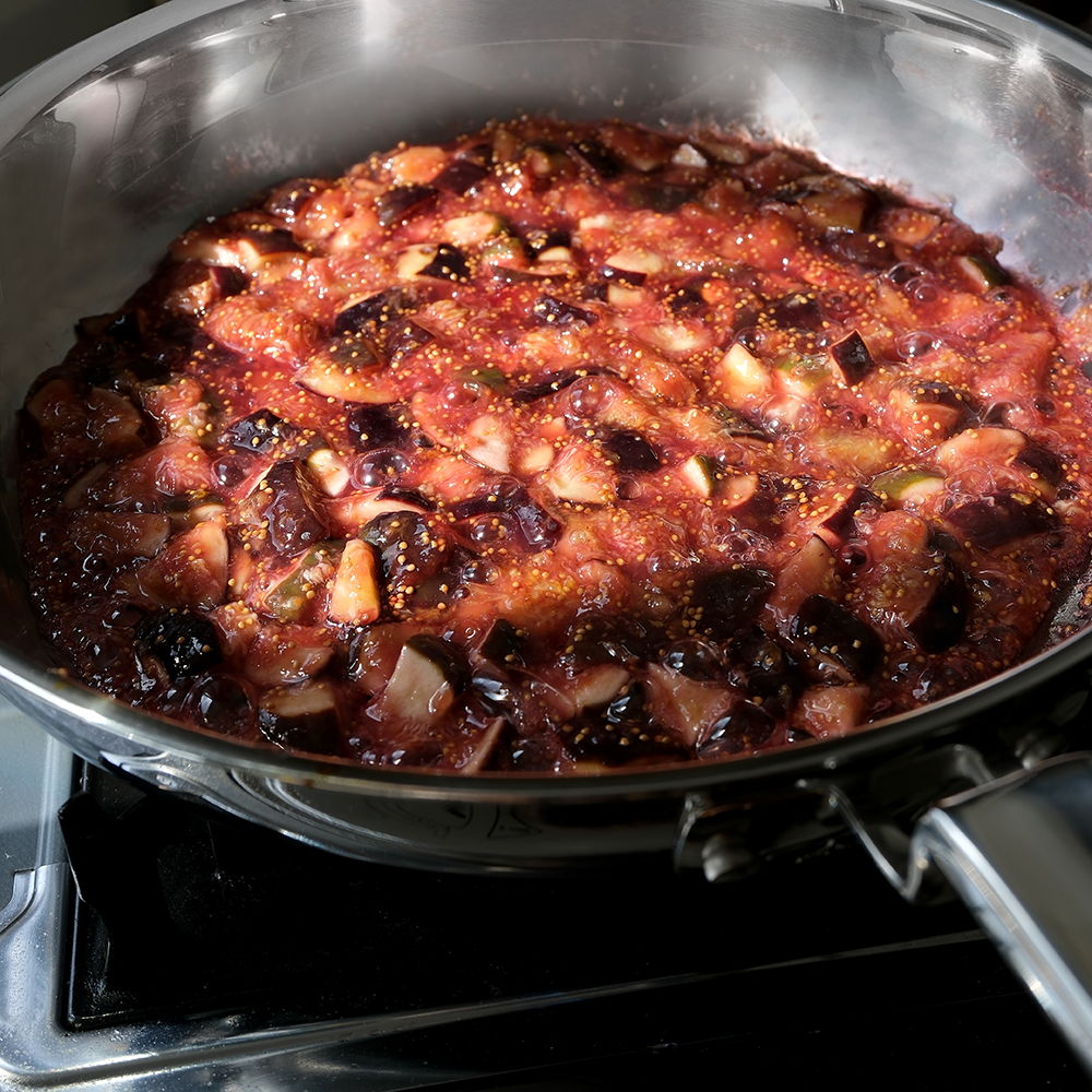A pan of simmering fruit mixture on a stovetop.