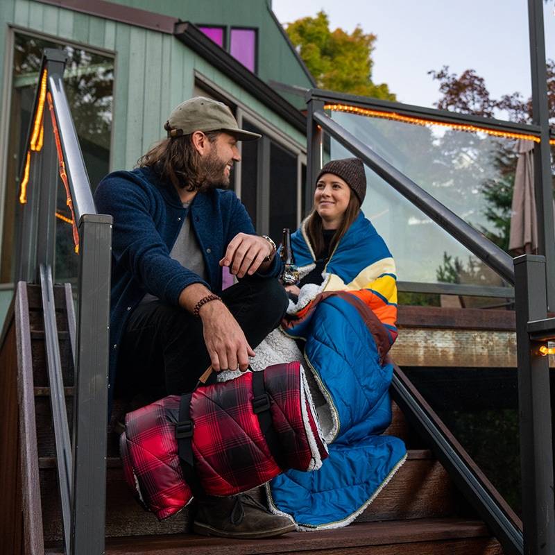 Couple sitting on deck wrapped in Sherpa Puffy blankets