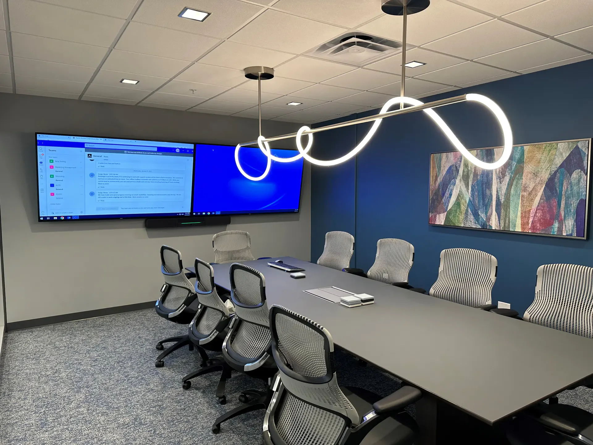 A modern conference room with a large table and screens.