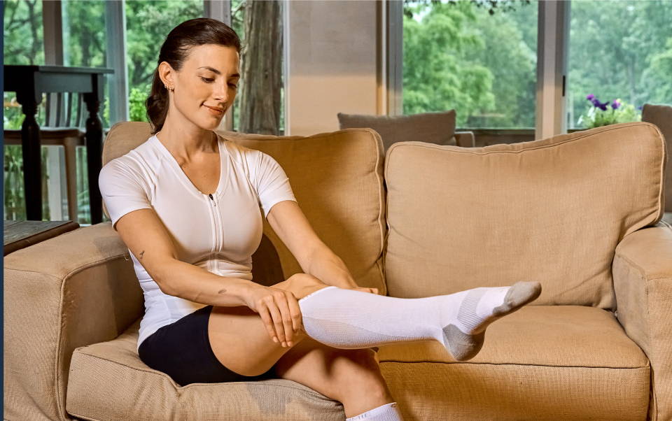 A woman putting on Tommie Copper compression socks
