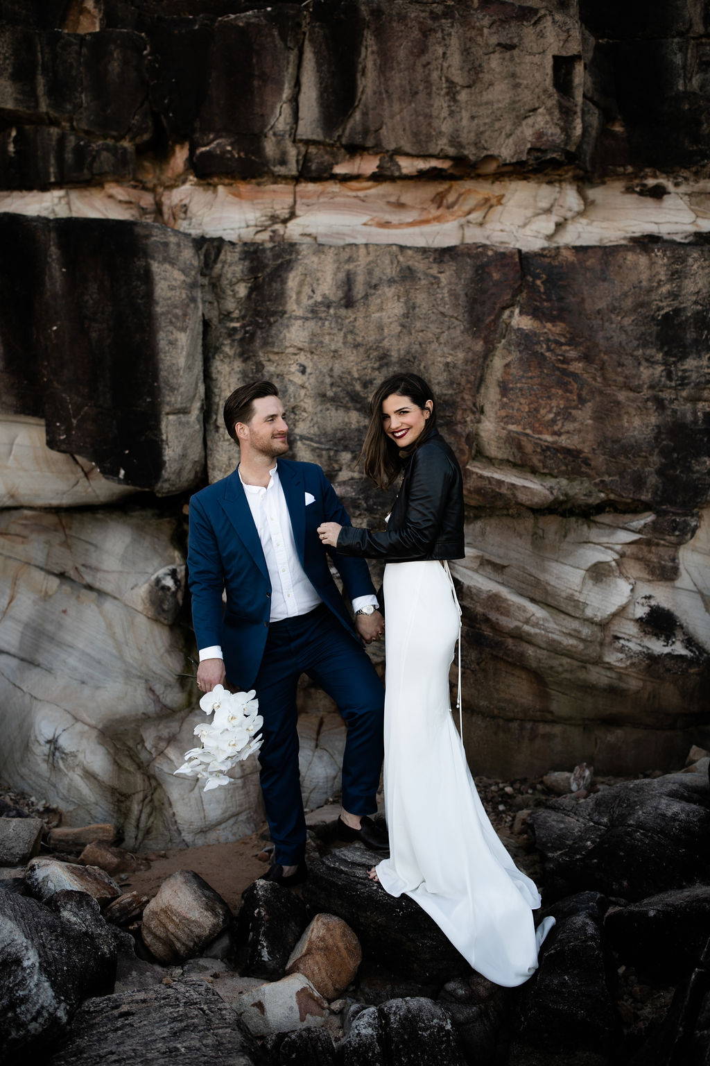 Bride wearing a black leather jacket over her silk wedding dress