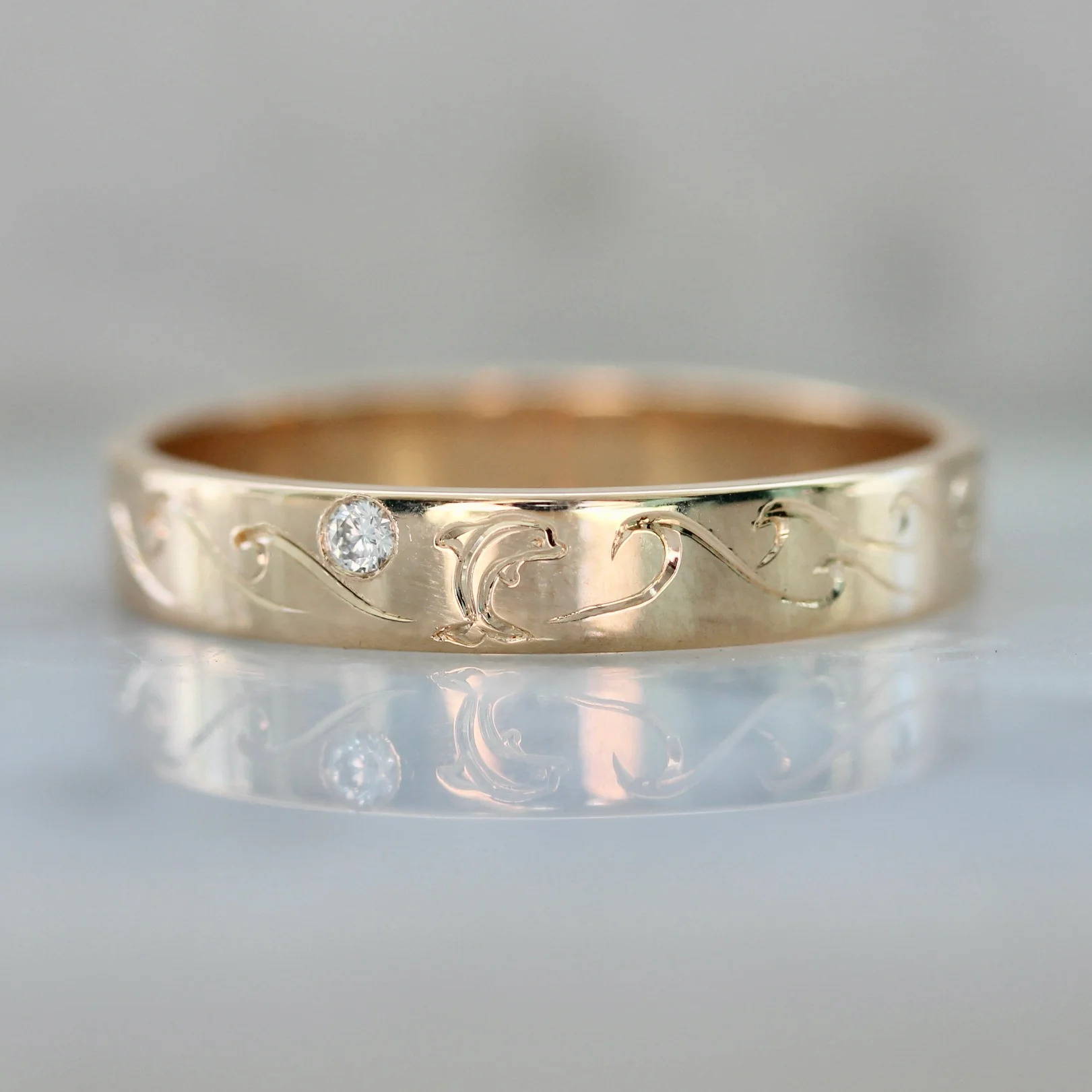 gold band with dolphin engraving and a diamond