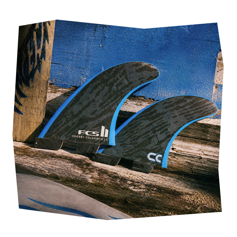 Trois Ailerons de planche de surf Ailerons contre une surface en bois.
