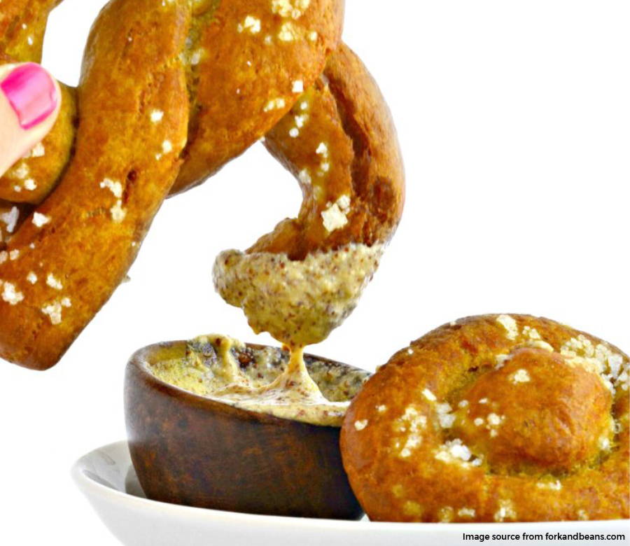 soft pretzel being dipped in sauce