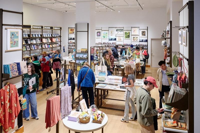People browsing in a museum gift store with shelves of books and merchandise.