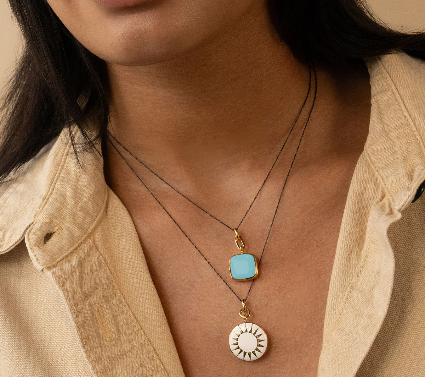 Close-up of a person wearing layered necklaces with various pendants.