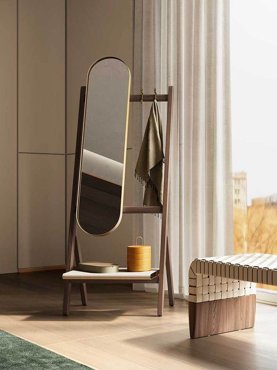 A standing mirror beside a chair and window in a modern room.