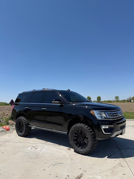 Driver-side front-three-quarter view Troy's black lifted 2018 Ford Expedition on concrete under clear blue sky gallery photo 20