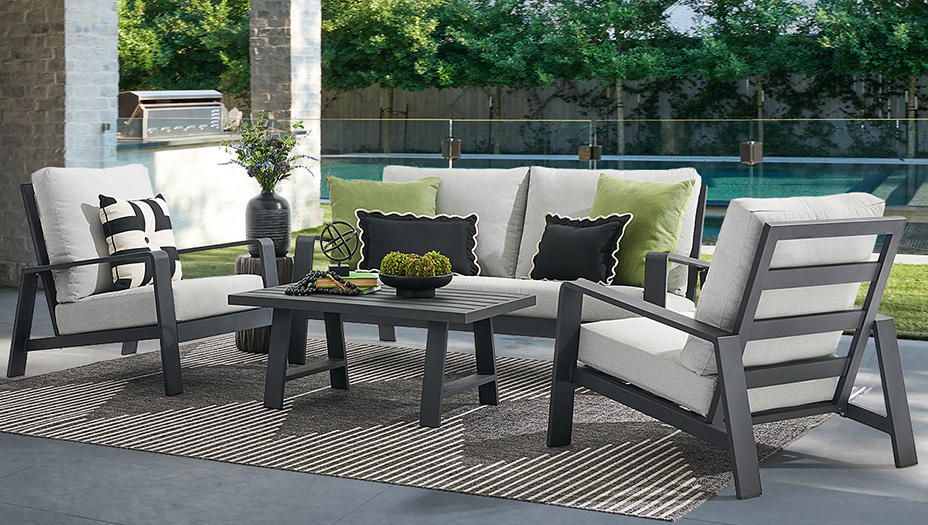Outdoor seating arrangement with cushions and a coffee table by a pool.