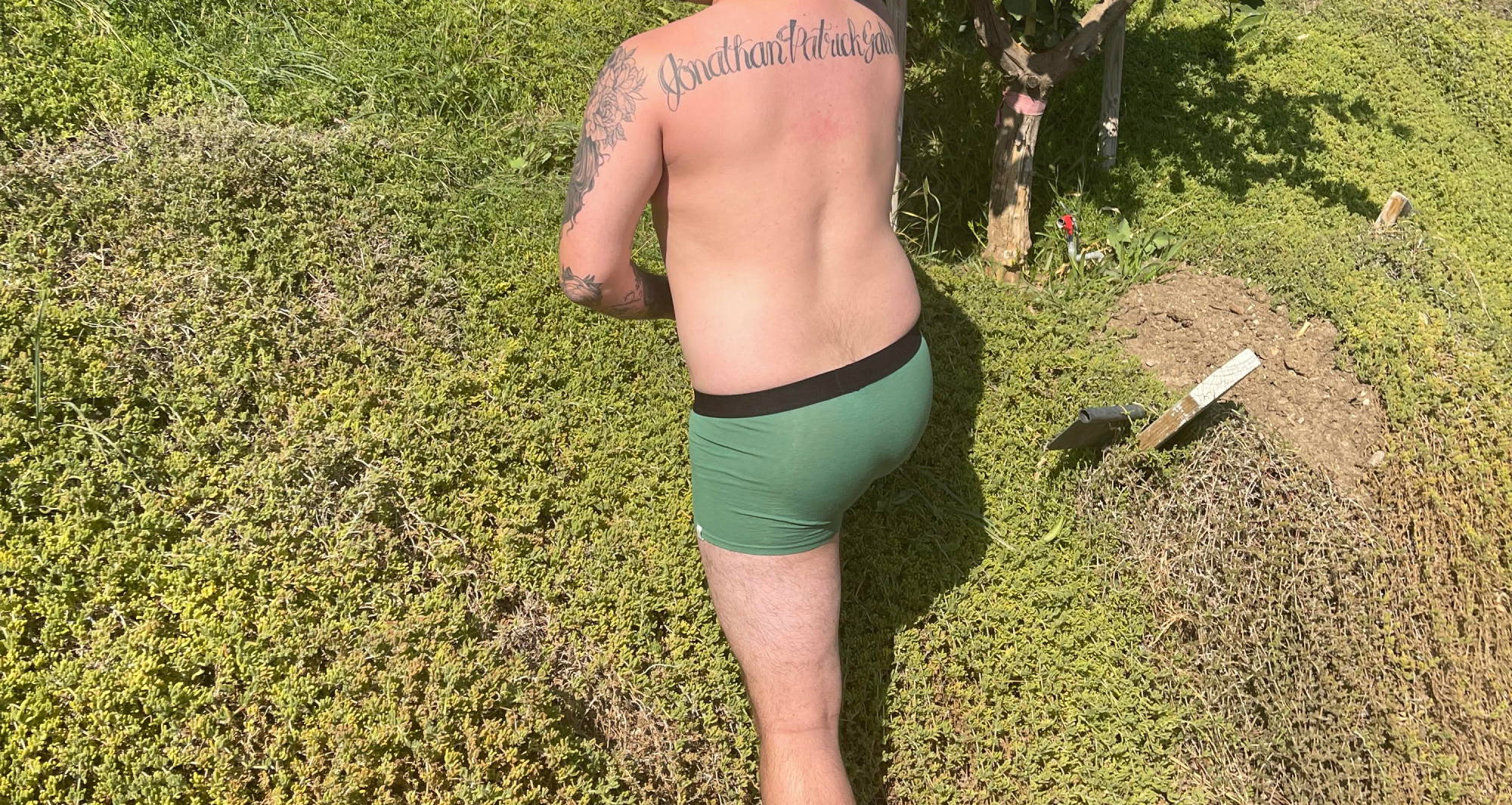 a man in green trunks underwear and a black cowboy hat from the back