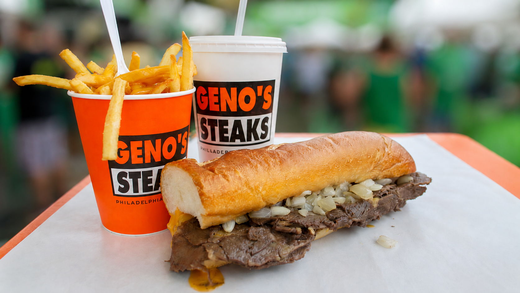 Cheesesteak sandwich with fries and drinks from Geno's Steaks.