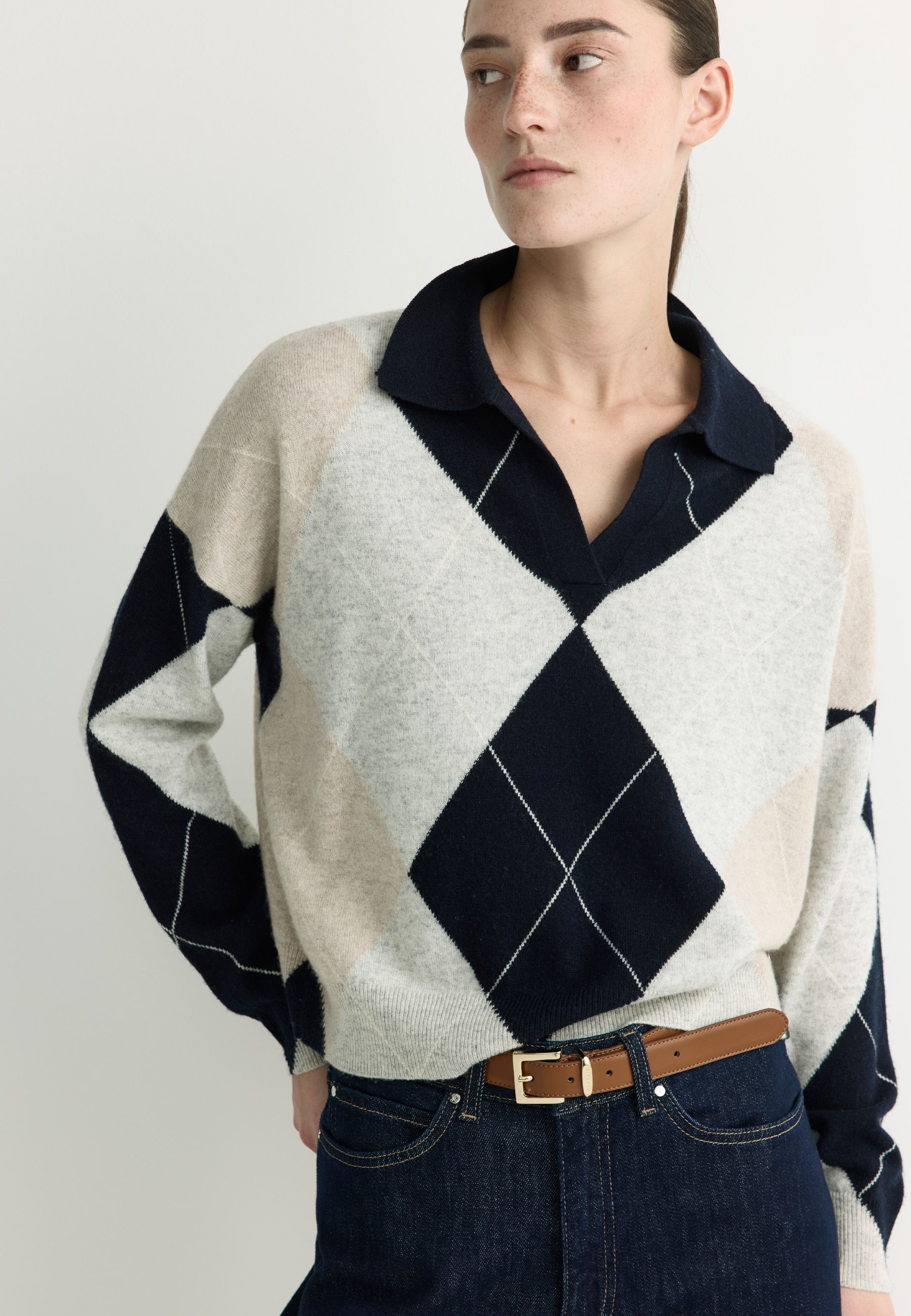 Woman wearing a patterned sweater with a collar and jeans.