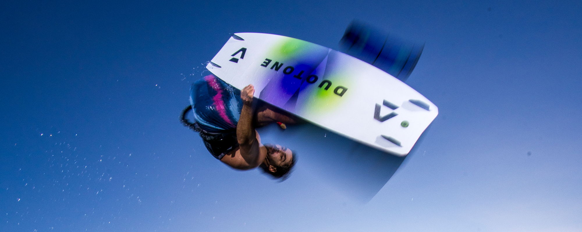 A person performing a trick on a wakeboard against a blue sky.
