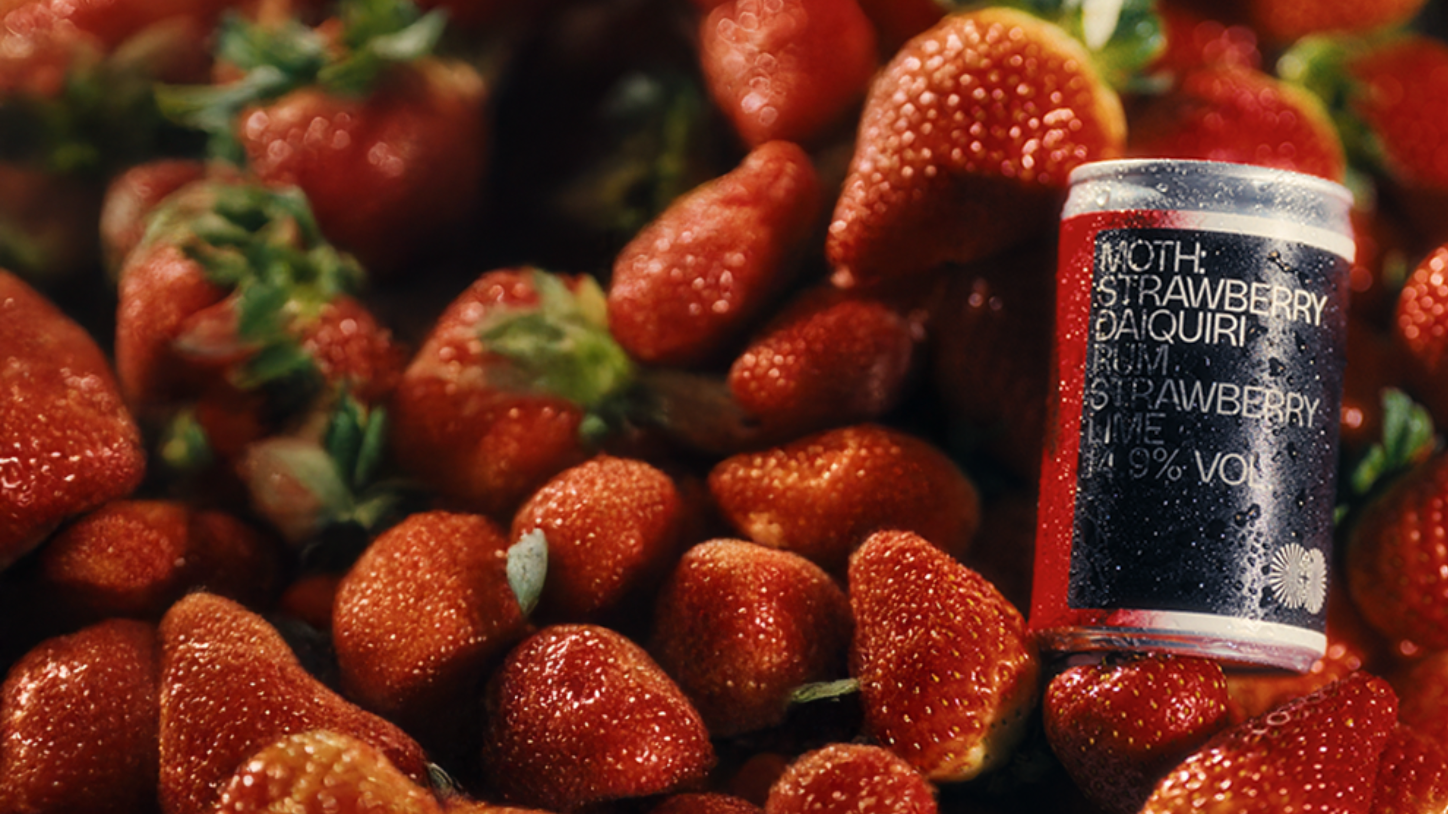 A can amidst a pile of fresh strawberries.