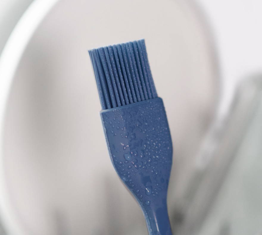 A Blue Misen Pastry Brush just washed in a dishwasher, covered in small water droplets.