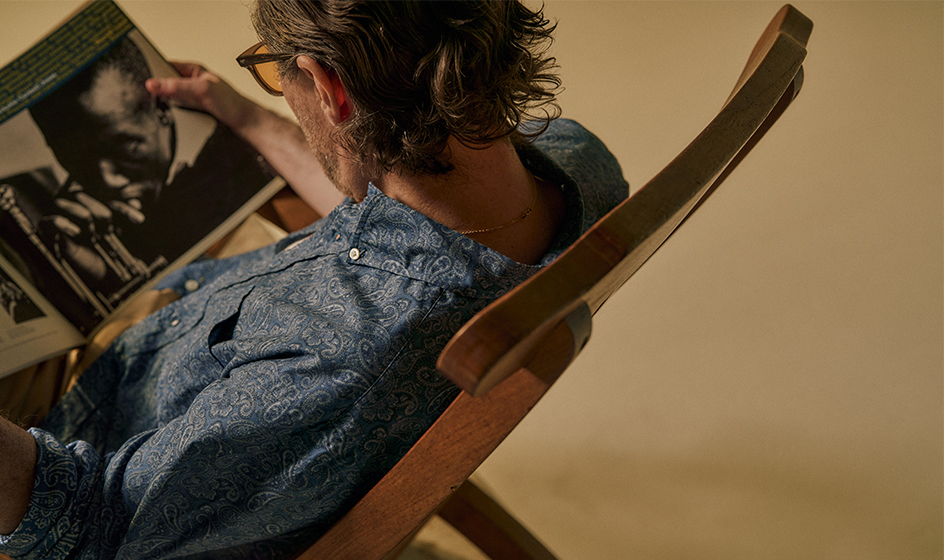 Person sitting in a chair, reading a book or magazine.