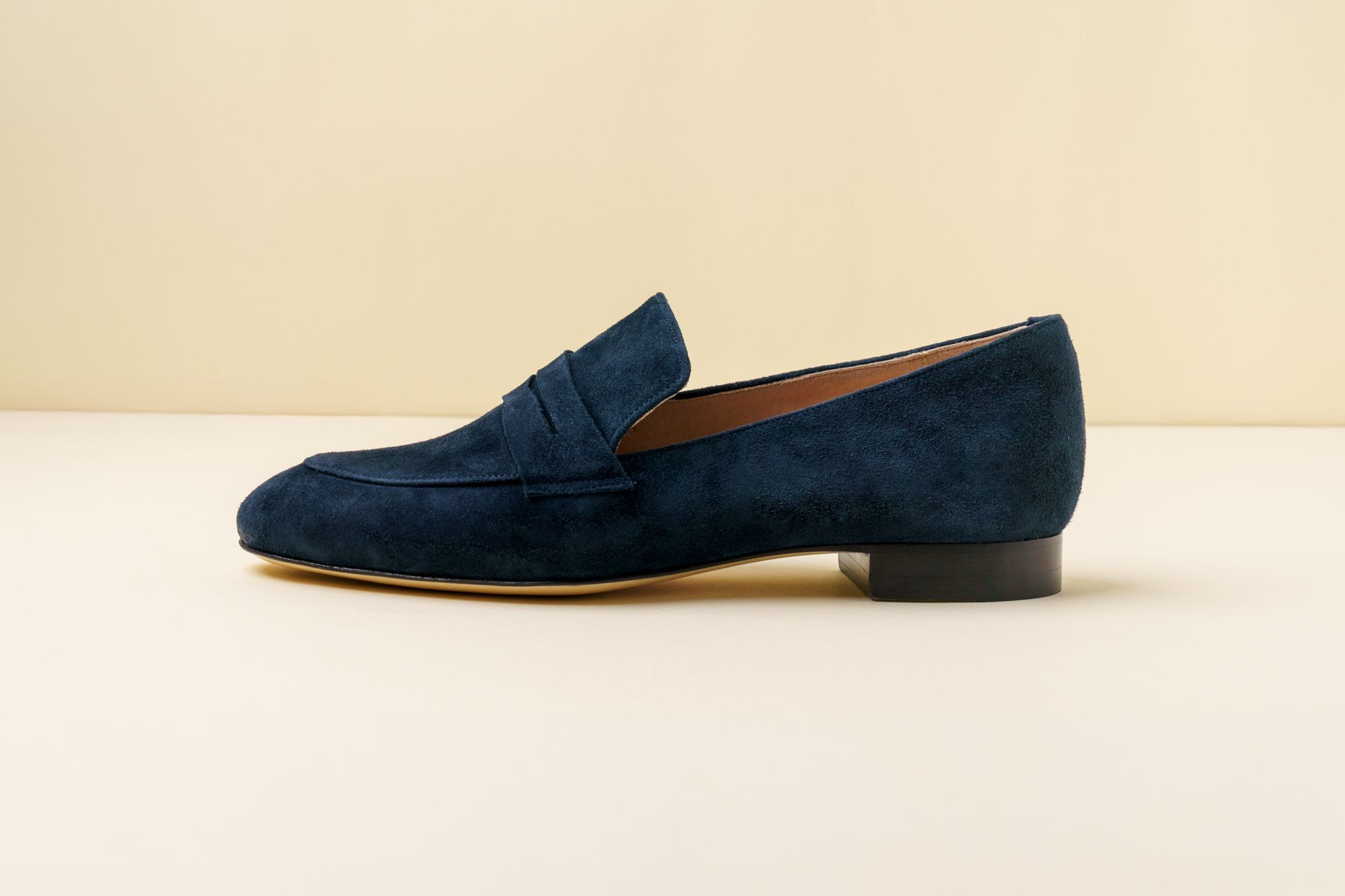 Navy blue suede loafers on a neutral background.
